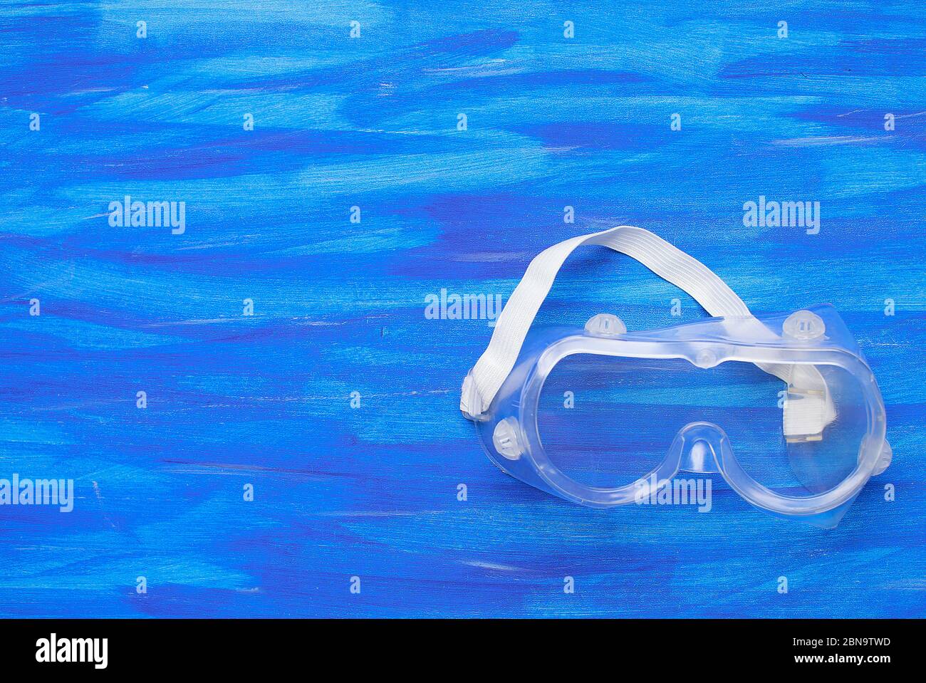 Plastic safety goggles on blue background Stock Photo