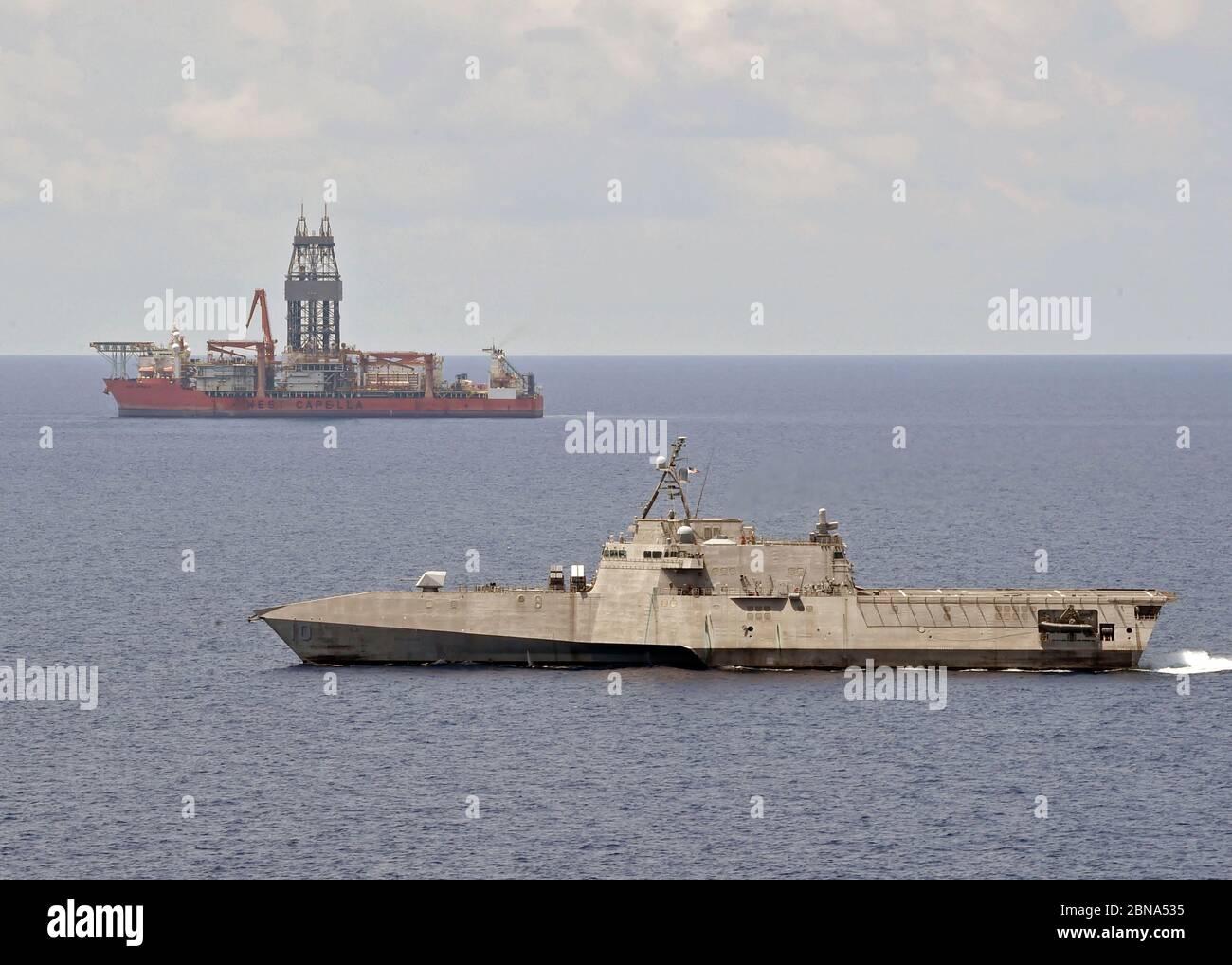 The U.S. Navy Independence-variant littoral combat ship USS Gabrielle Giffords patrols near the Panamanian flagged drill ship, West Capella which has been harassed by Chinese forces for drilling in disputed waters May 12, 2020 in the South China Sea. Stock Photo