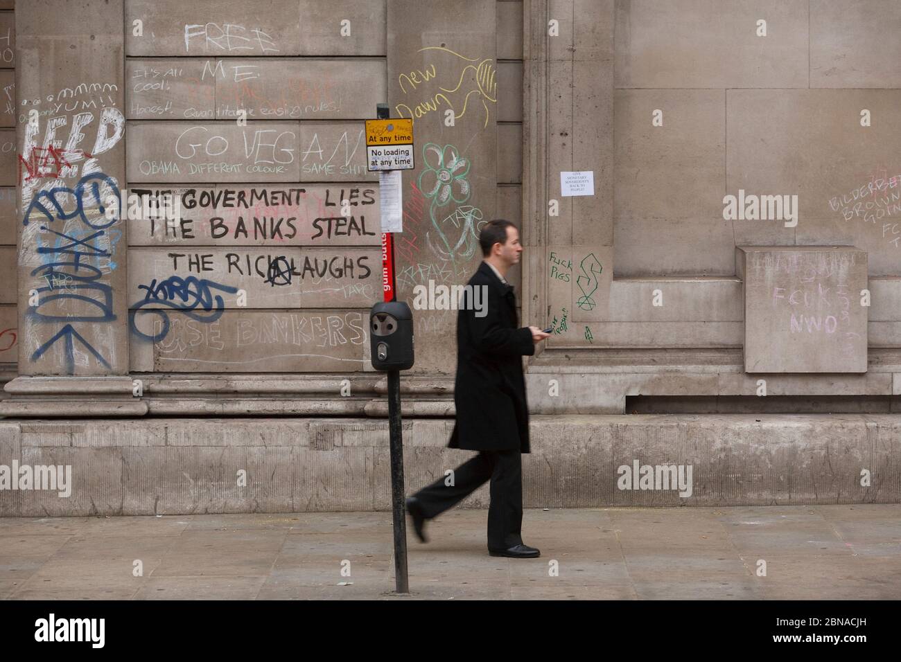 Anti G20 protests, city worker walking past graffiti on the Bank of England, City of London, UK Stock Photo