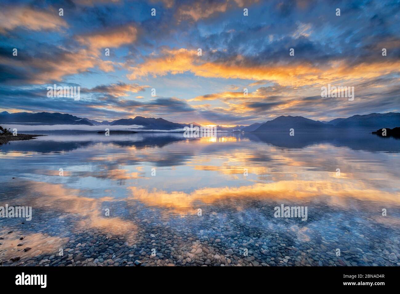 Light beam of golden cloud atmosphere over Lake Te Anau, in the background mountain ranges of the Stuart Mountains and Franklin Mountains, Fjordland N Stock Photo