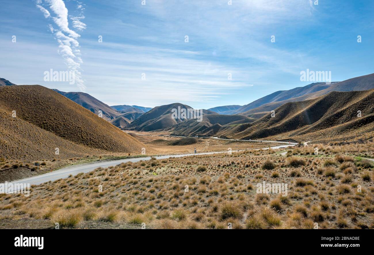 Barren mountain landscape with tufts of grass, pass road, Lindis Pass, Southern Alps, Otago, South Island, New Zealand, Oceania Stock Photo