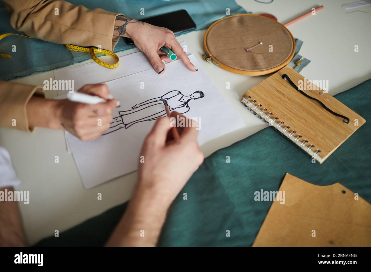 Close-up of two fashion designers drawing sketch of new dress with pencils together Stock Photo