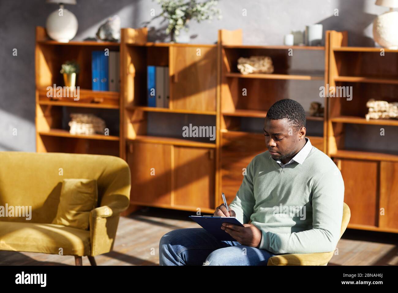 African man sitting on chair and making notes in document at the office Stock Photo