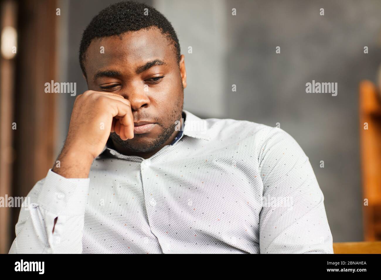 African young man sitting with sad look or thinking about something Stock Photo