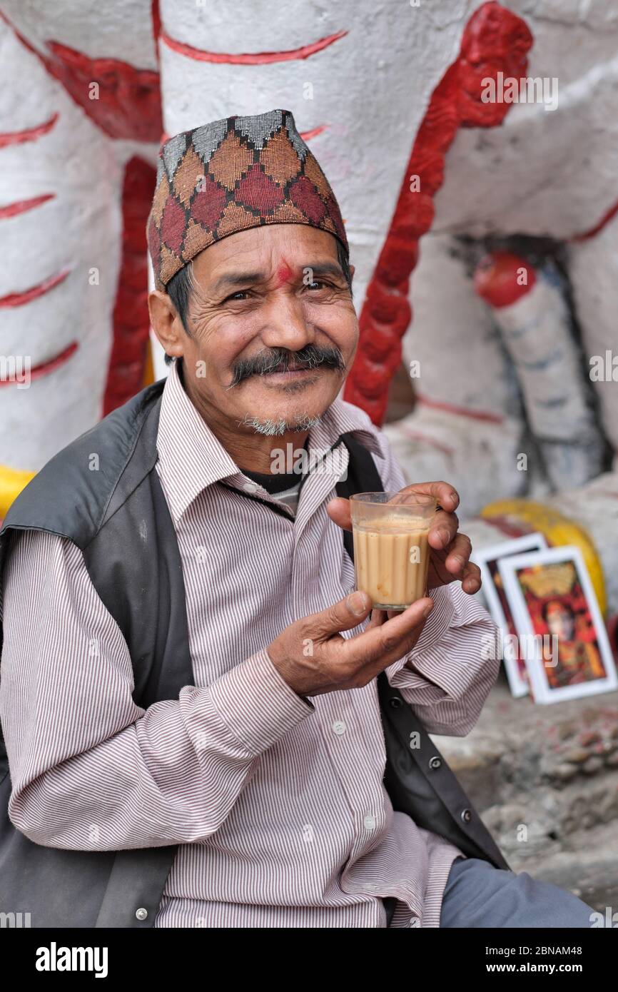 A man of the Newar community, with traditional Nepalese topi (cap), enjoying a glass of milk tea, Kathmandu, Kathmandu Valley, Nepal Stock Photo