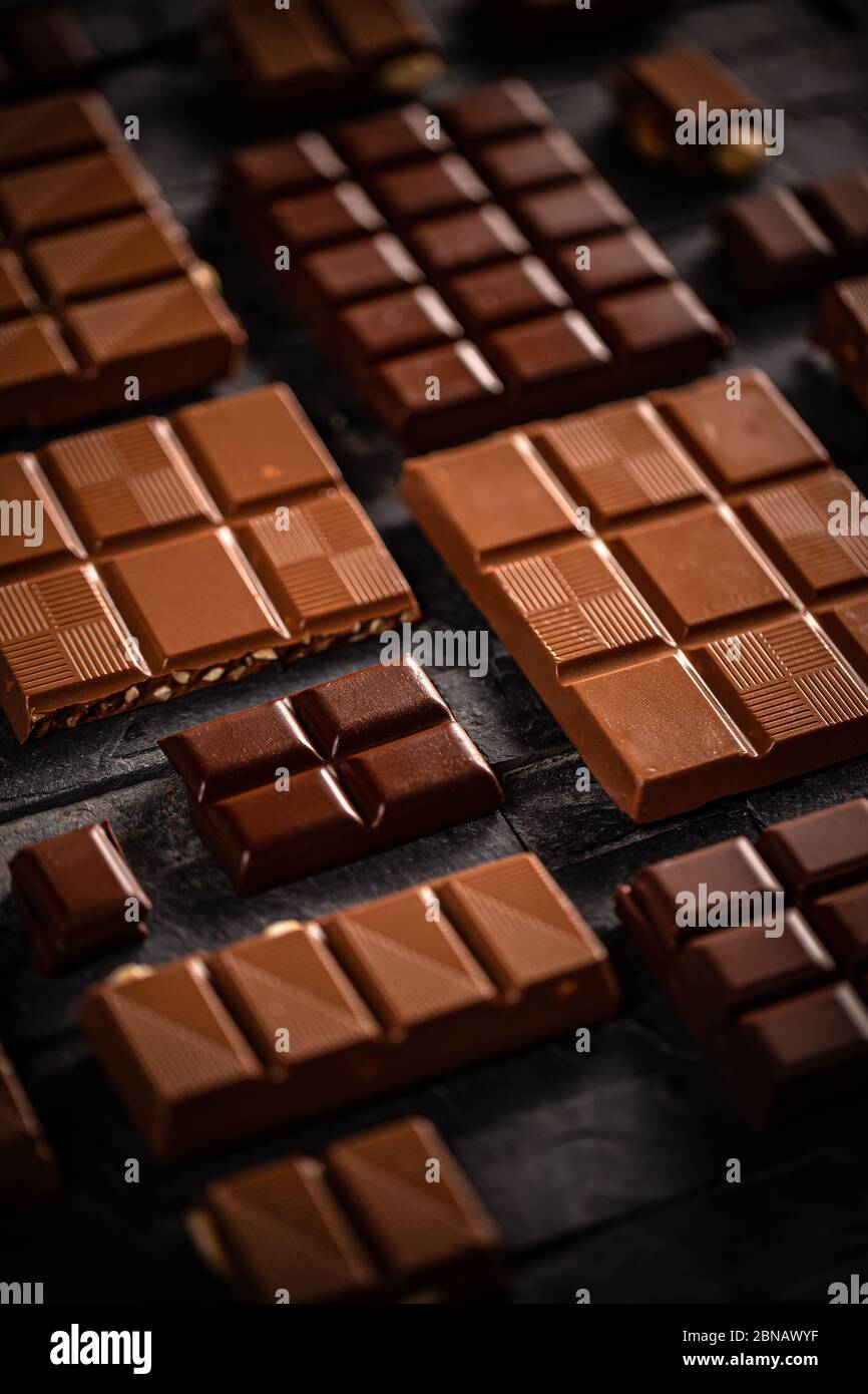 Sweet milk and hazelnut chocolate bar pieces on black background Stock Photo