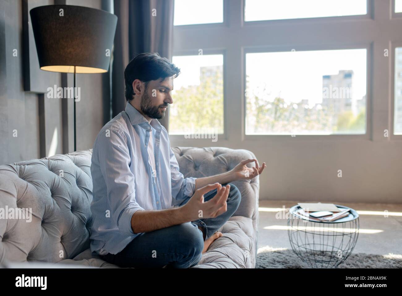 Cute calm man sitting in a pose on the couch. Stock Photo