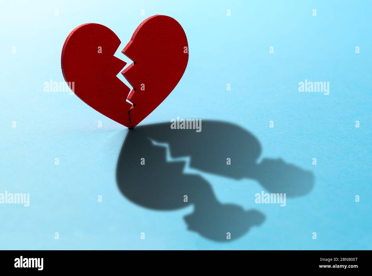 Broken heart. Crack in the red heart, Breaking the relationship. Shadow from the heart in the form of two figures of man and woman. Stock Photo