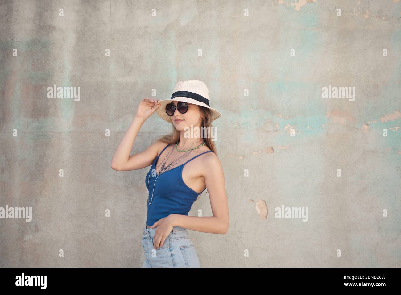 Beautiful shot of a female in blue sleeveless wearing sunhat and glasses and other accessories Stock Photo