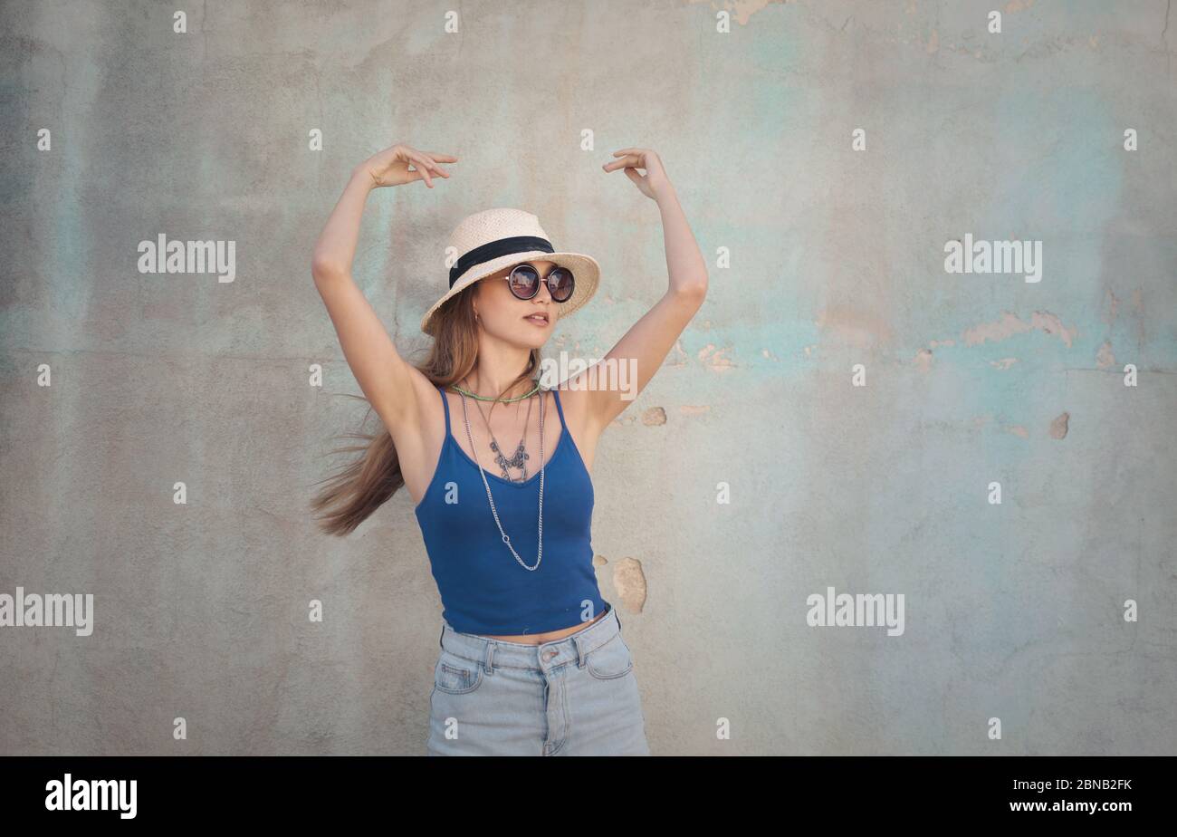 Beautiful shot of a female in blue sleeveless wearing sunhat and glasses and other accessories Stock Photo