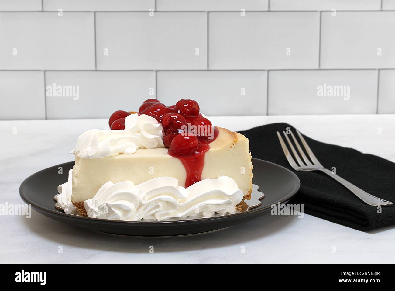 One slice of delicious New York cheesecake garnished with cherries and whipped cream. Stock Photo