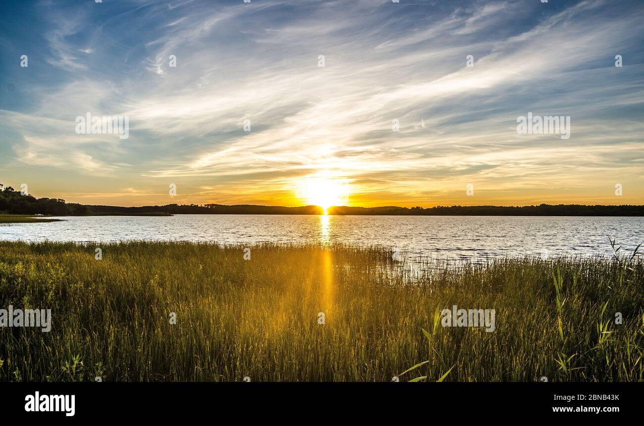 Beautiful scenery of the sunset reflecting on the sea under a cloudy sky Stock Photo