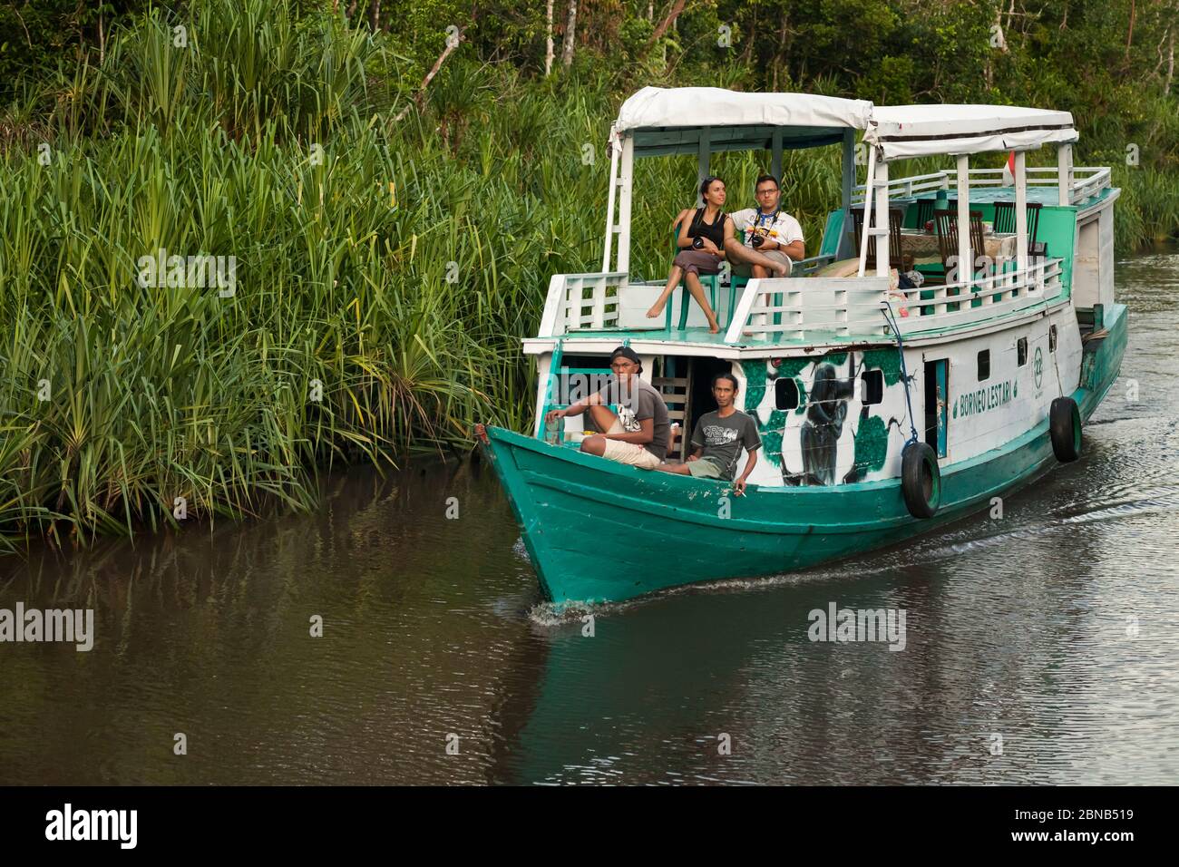 Couple of tourists navigating in a traditional wooden Klotok through the Sekonyer River, Tanjung Puting National Park, Borneo, Indonesia Stock Photo