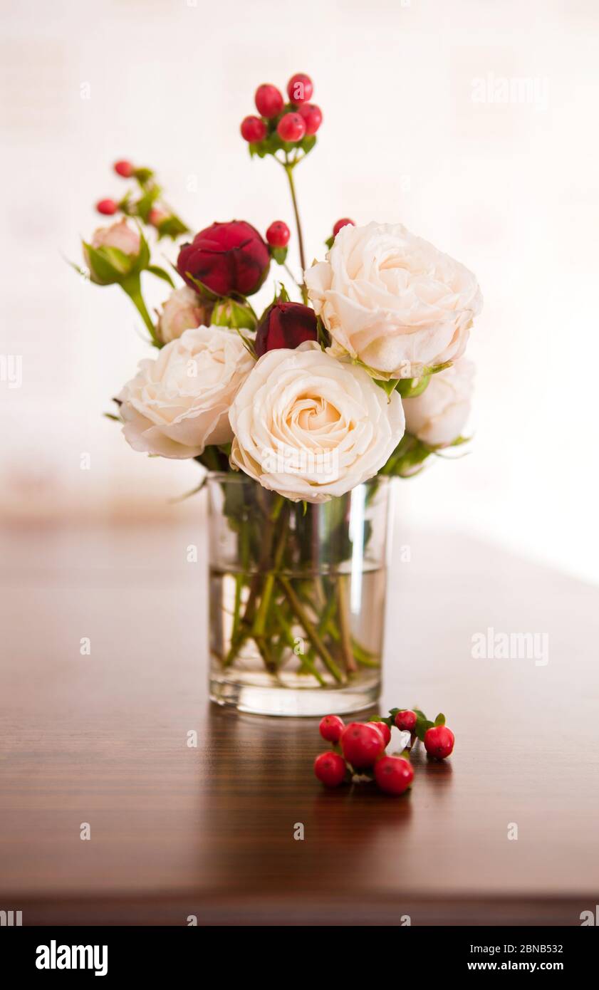 roses and red hypericum berries in a glass Stock Photo