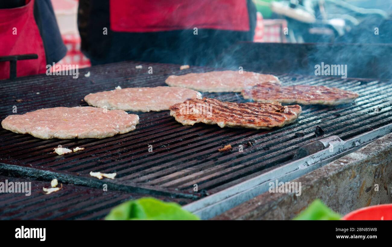 Beef burgers cooking on griddle plate. Fry on an open fire on the grill
