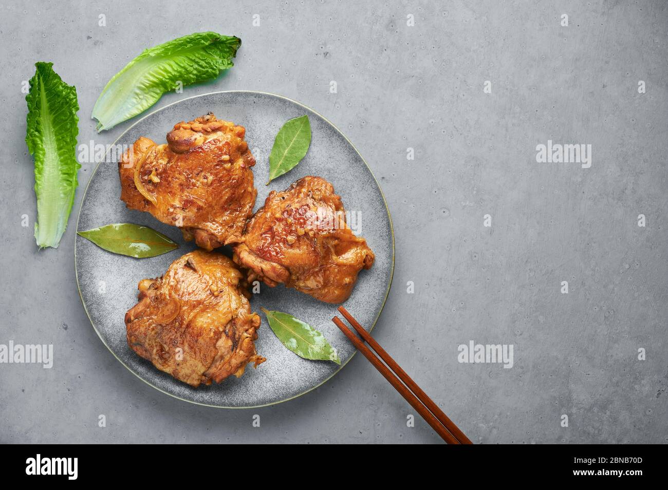 Filipino Chicken Adobo on gray plate on concrete backdrop. Chicken