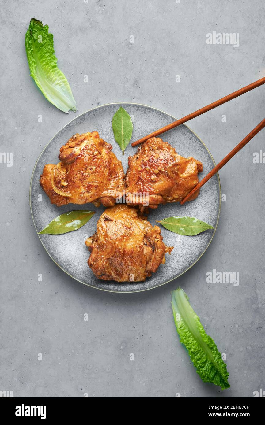 Filipino Chicken Adobo on gray plate on concrete backdrop. Chicken
