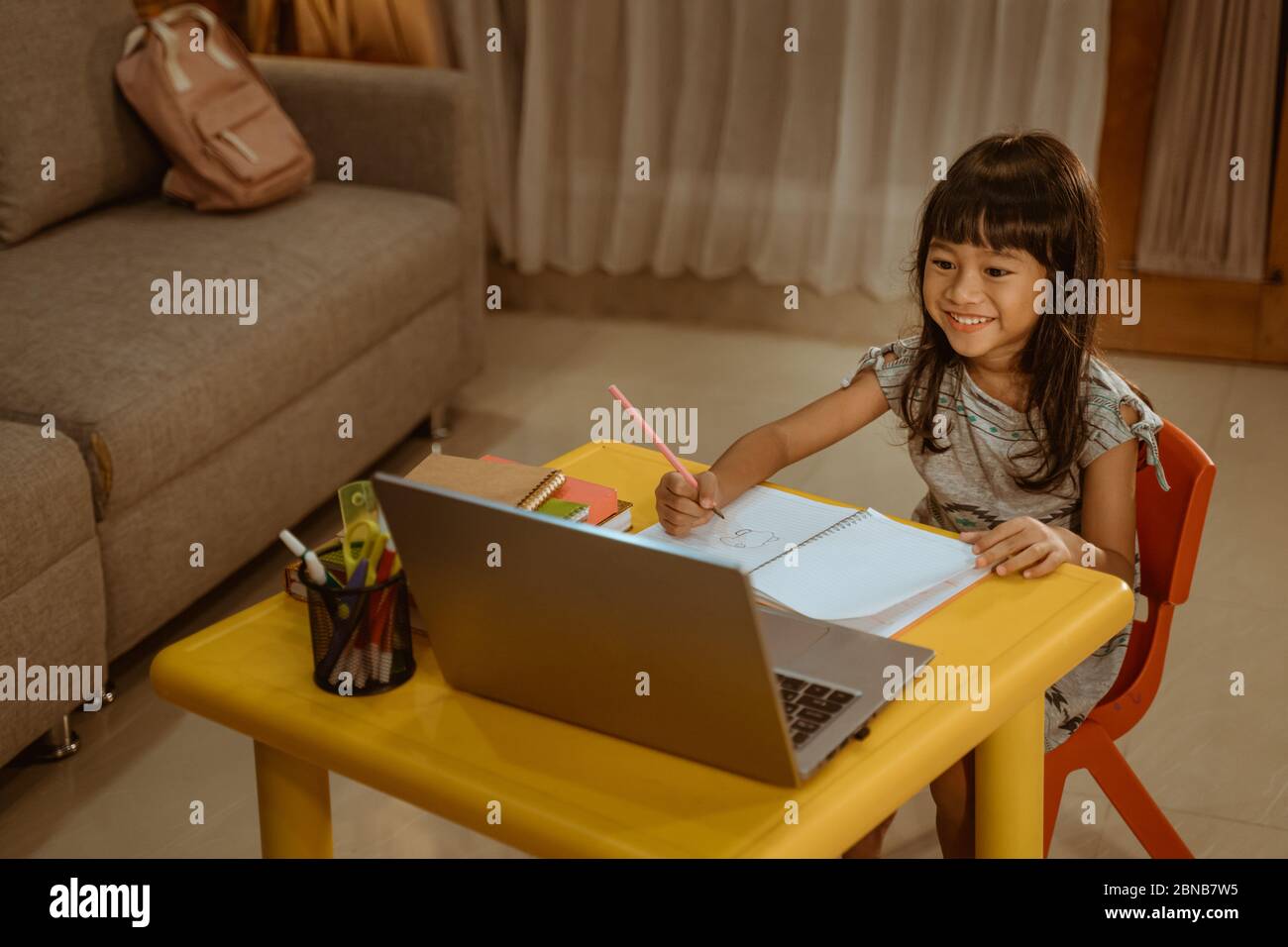 happy little girl doing homework using laptop at home Stock Photo - Alamy