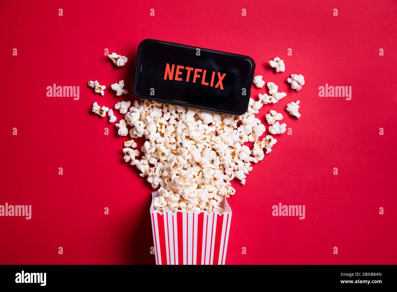 LONDON, UK - MAY 14 2020: Netflix logo on a smartphone with popcorn Stock Photo