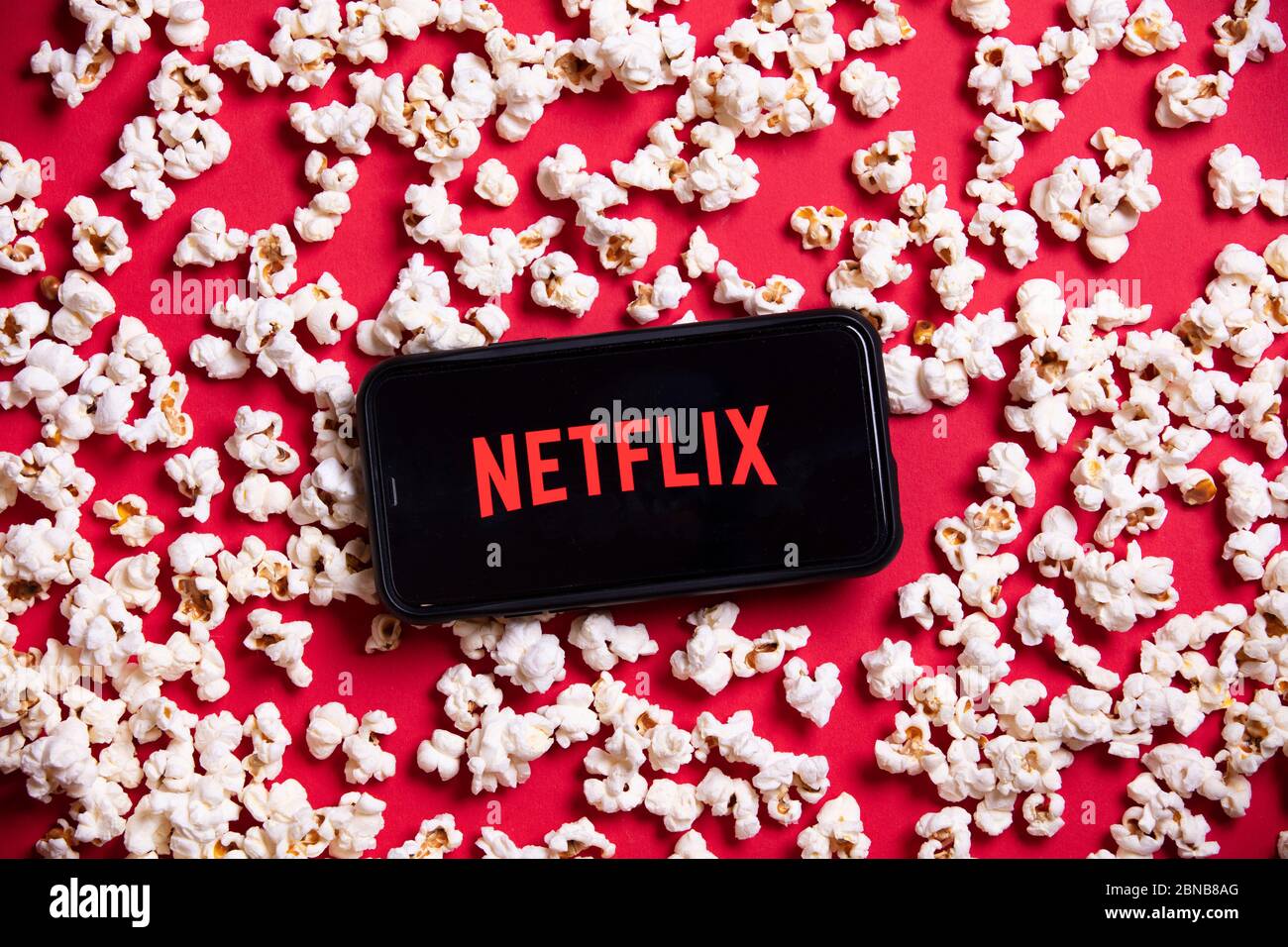 LONDON, UK - MAY 14 2020: Netflix logo on a smartphone with popcorn Stock Photo