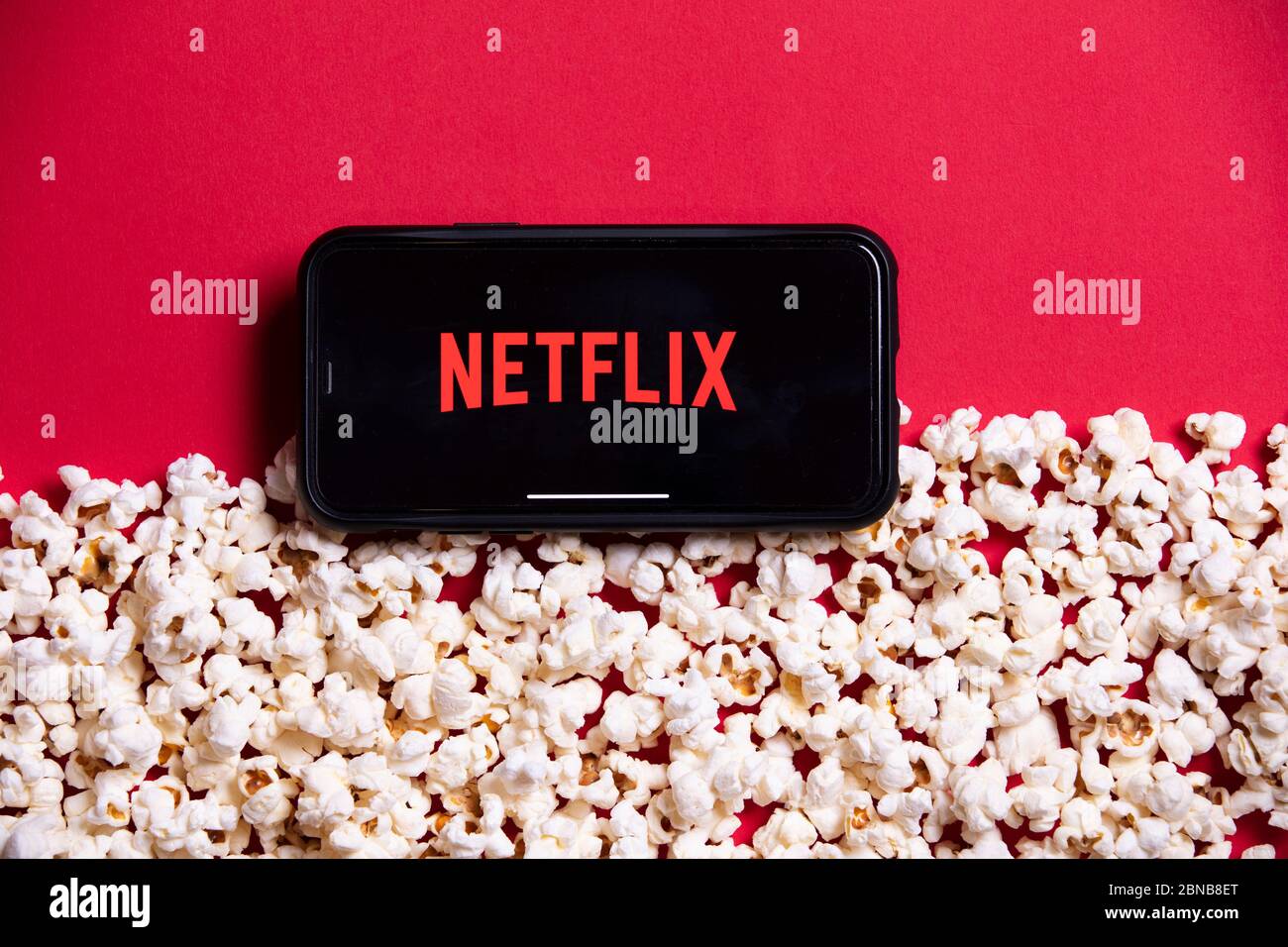 LONDON, UK - MAY 14 2020: Netflix logo on a smartphone with popcorn Stock Photo