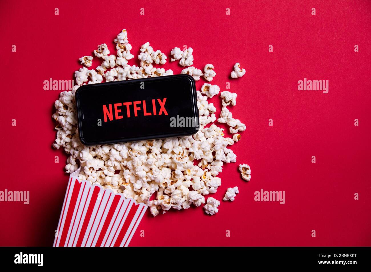 LONDON, UK - MAY 14 2020: Netflix logo on a smartphone with popcorn Stock Photo