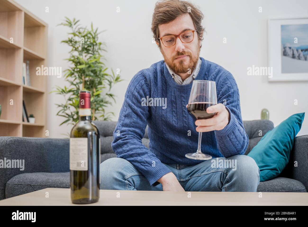 Portrait of man with alcohol drink sitting on sofa at home Stock Photo
