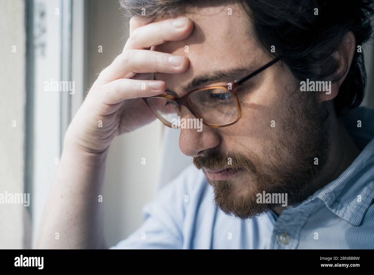 Thoughtful anxious guy looking out the window Stock Photo