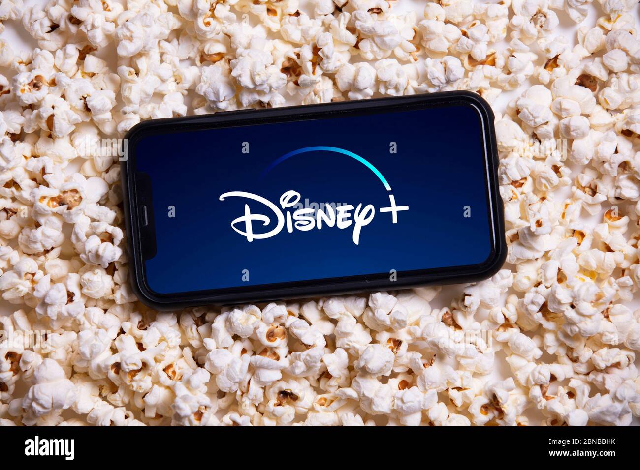 LONDON, UK - MAY 14 2020: Disney plus logo on a smartphone with popcorn Stock Photo