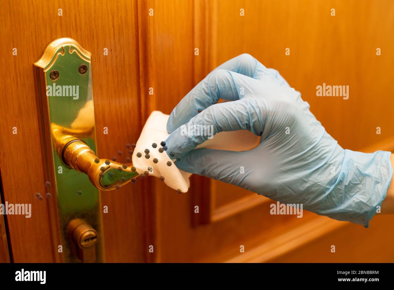 Woman cleaning the door knob of the house and using a disinfecting wipe Stock Photo