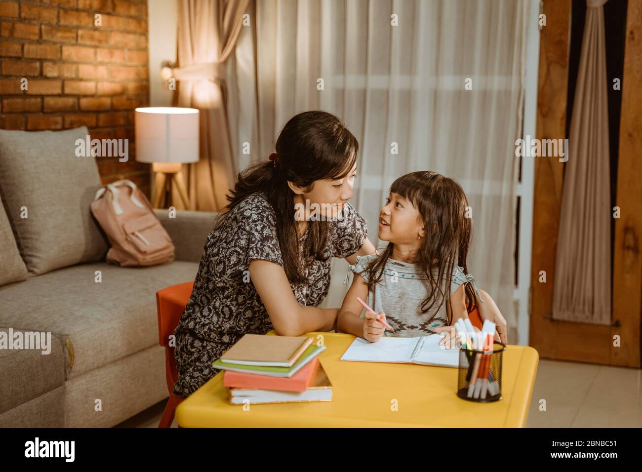 child do homework at home in the evening. mother help her daughter to ...