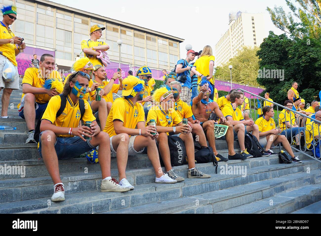 Drunk Swedish soccer fans, faces painted in yellow blue national colors  sitting on steps, plastic glasses with beer in hands. Euro-2012. July 1,  2012 Stock Photo - Alamy