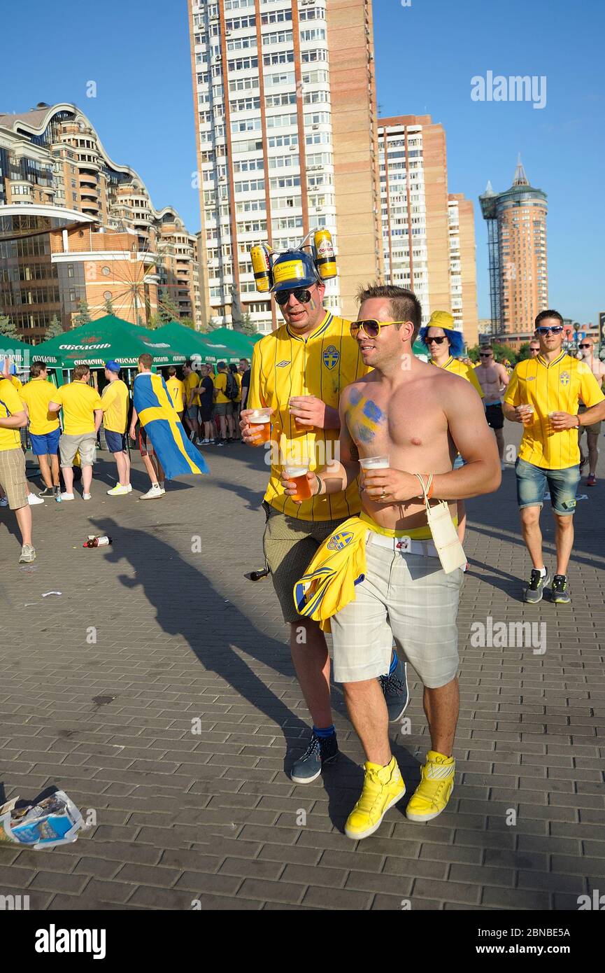 Swedish soccer fans standing and lying on a ground with glasses of beer in hands. Euro-2012, Swedish camp. July 1, 2012. Kiev, Ukraine Stock Photo