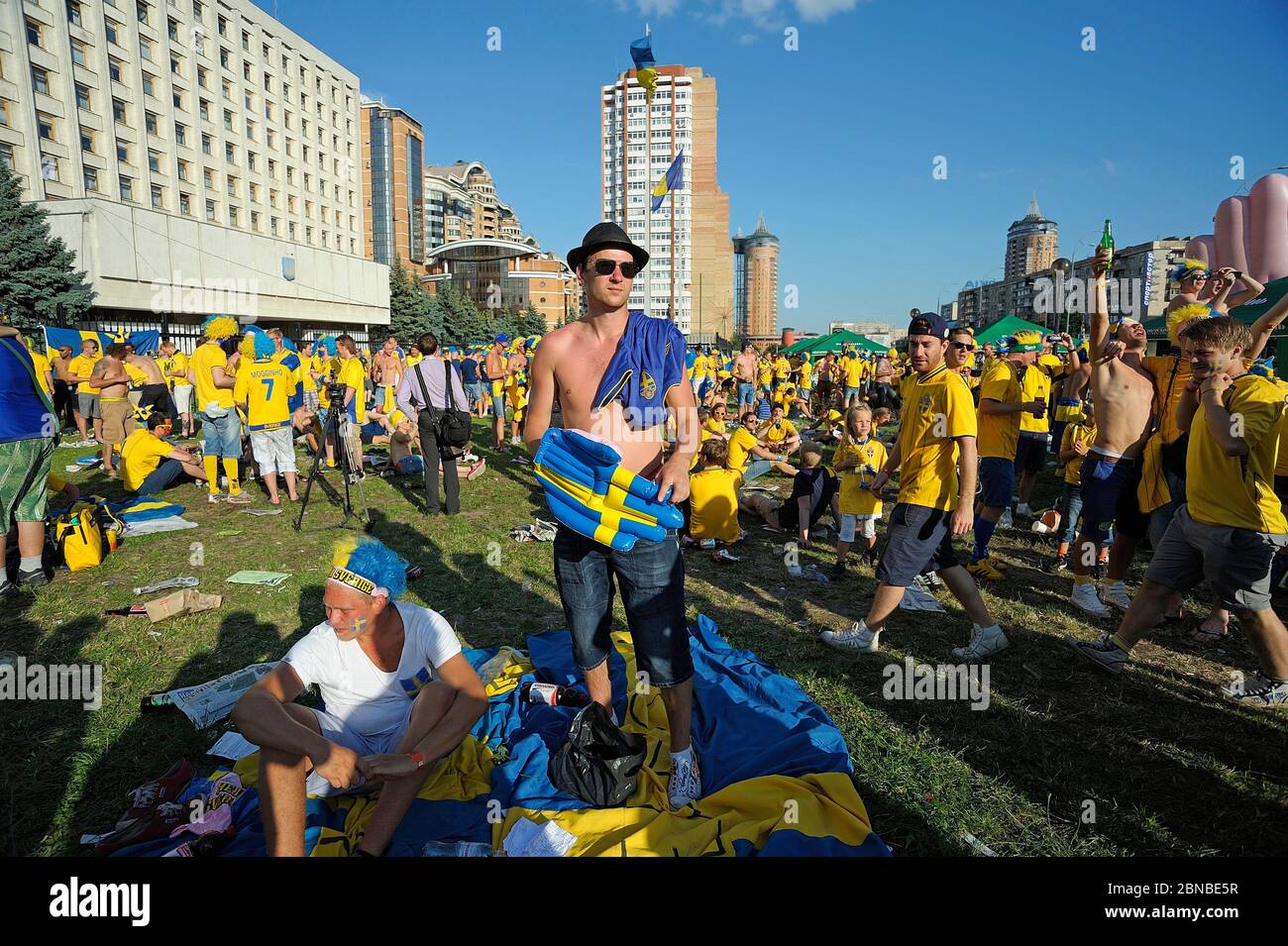 Swedish soccer fans standing and lying on a ground with glasses of beer in hands. Euro-2012, Swedish camp. July 1, 2012. Kiev, Ukraine Stock Photo