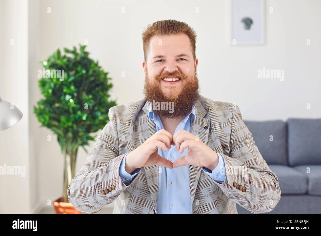 Online dating video chat call. Funny man with a beard looks at the camera online holds Online dating video chat call. Funny man with a beard looks at the camera online holds
