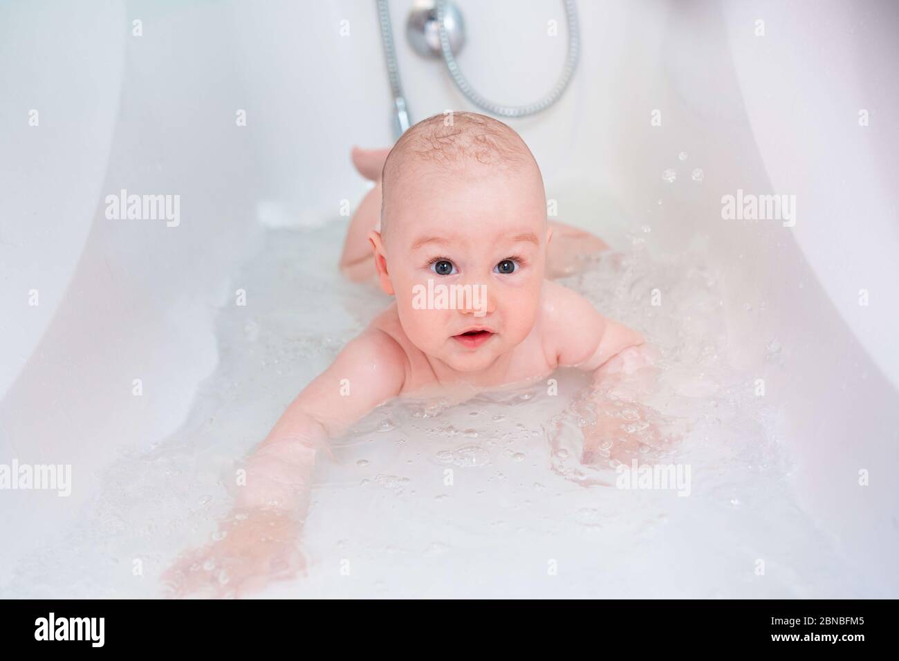 A pretty son bathes in a bath. Little child in a bathtub. Smiling kid