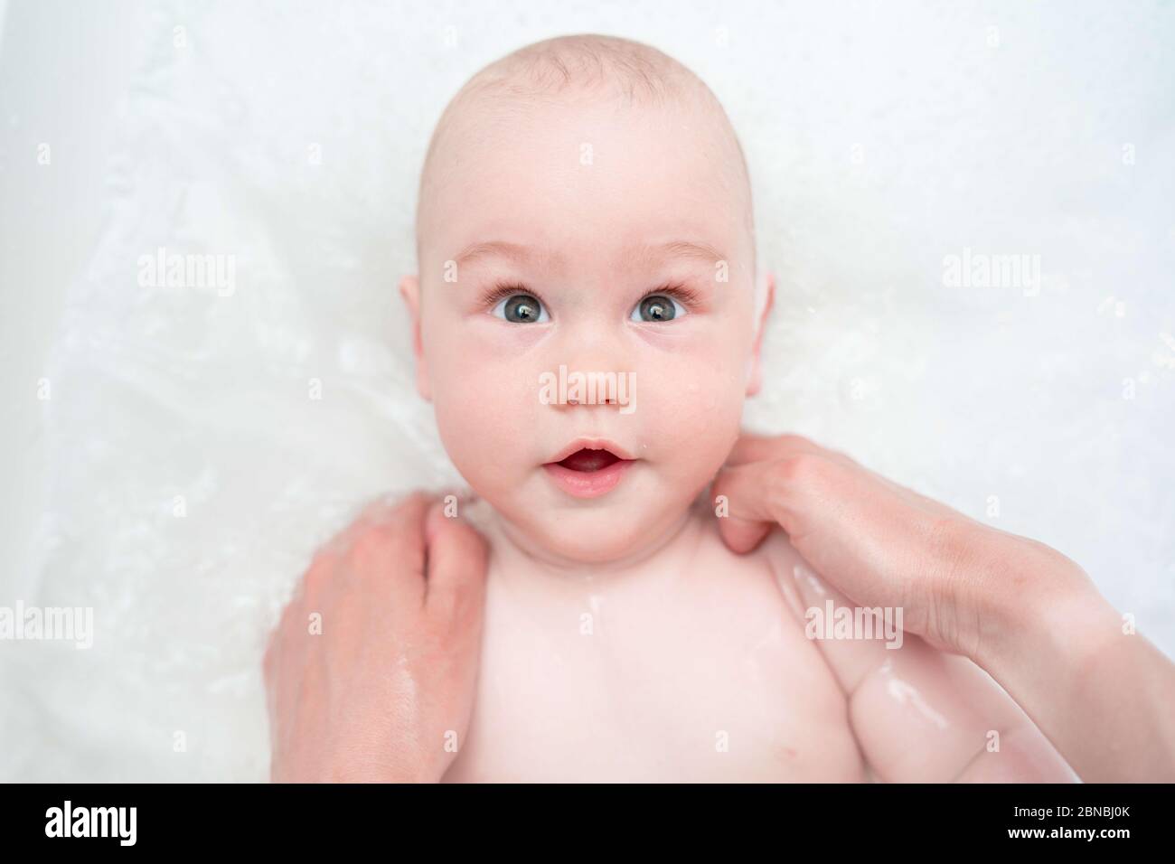 Adorable bath boy. Newborn baby bathing. Caring mother's hands. Hygiene