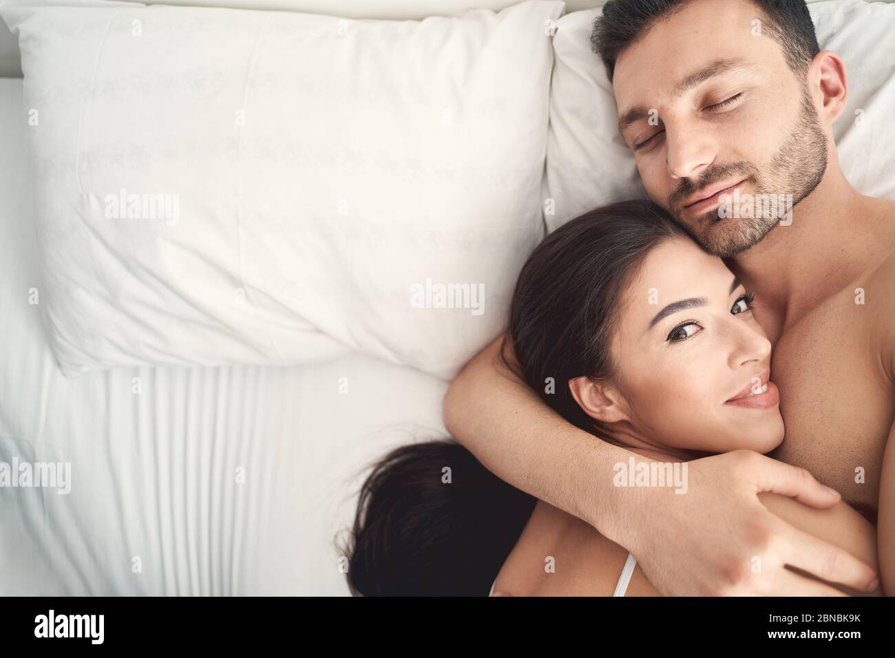 Young man hugging his wife during sleep Stock Photo Alamy