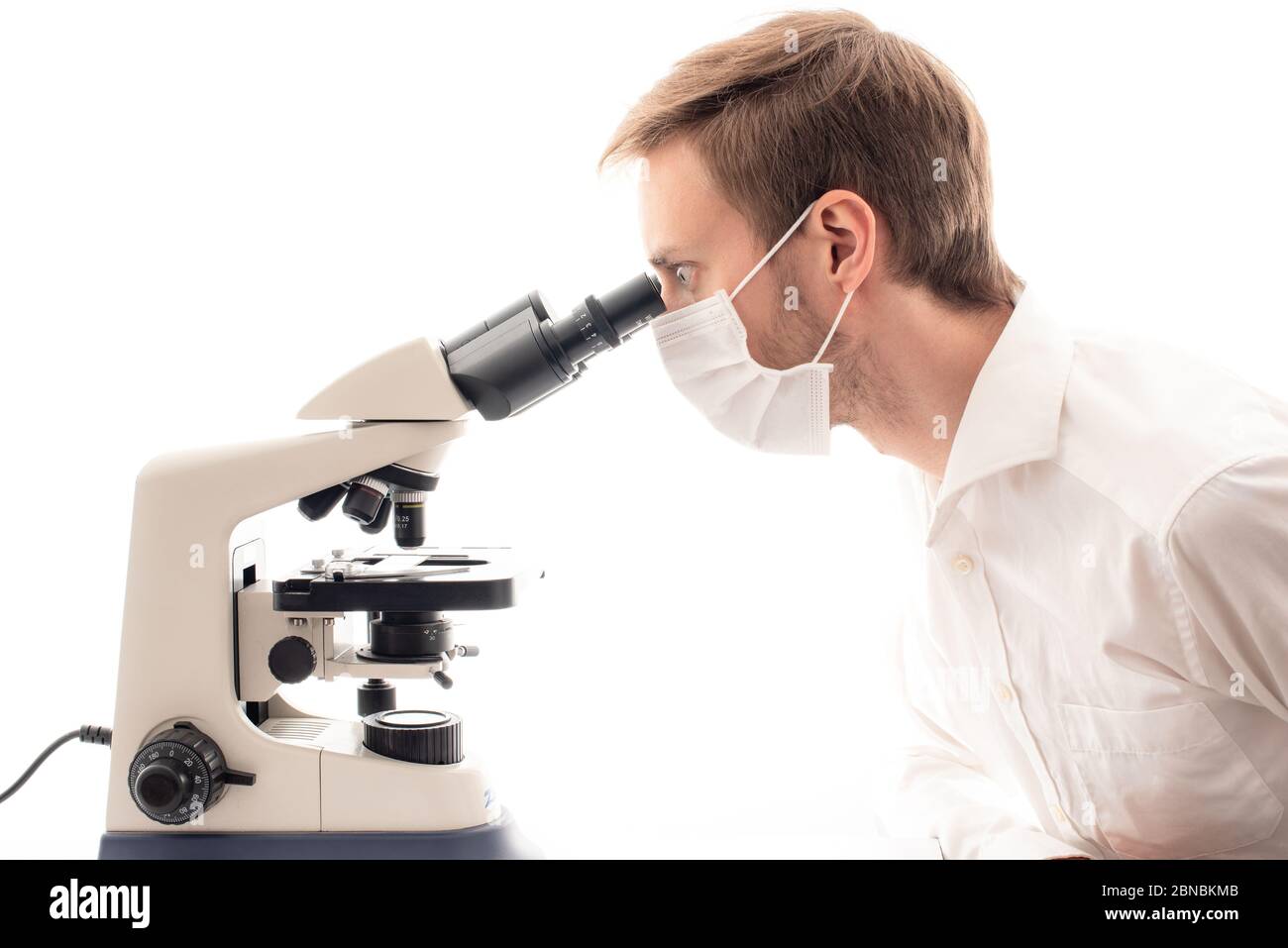 Profile photo of white male scientist using a binocular microscope, with a serious look to his eyes. Stock Photo