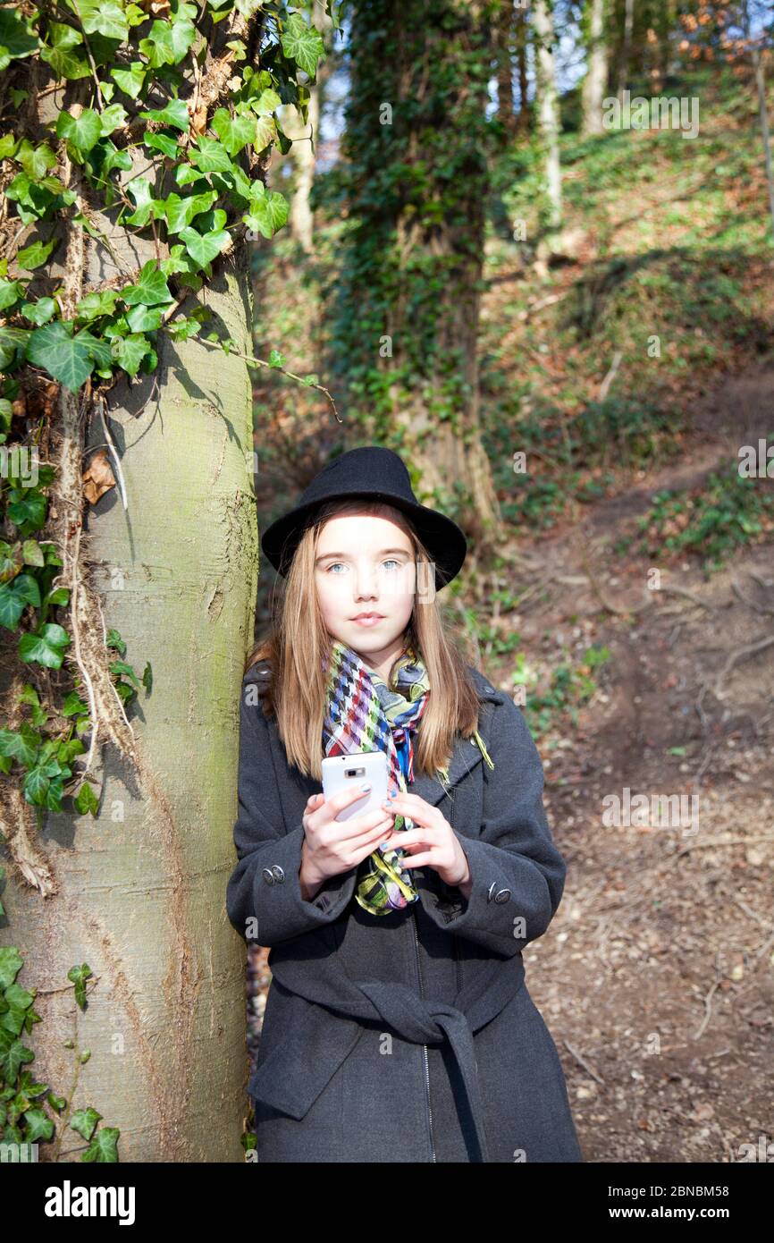 Young girl wearing hat using smartphone, girl wearing hat, girl in hat, girl using phone, teen using phone, teen using mobile phone, teen girl in hat, Stock Photo