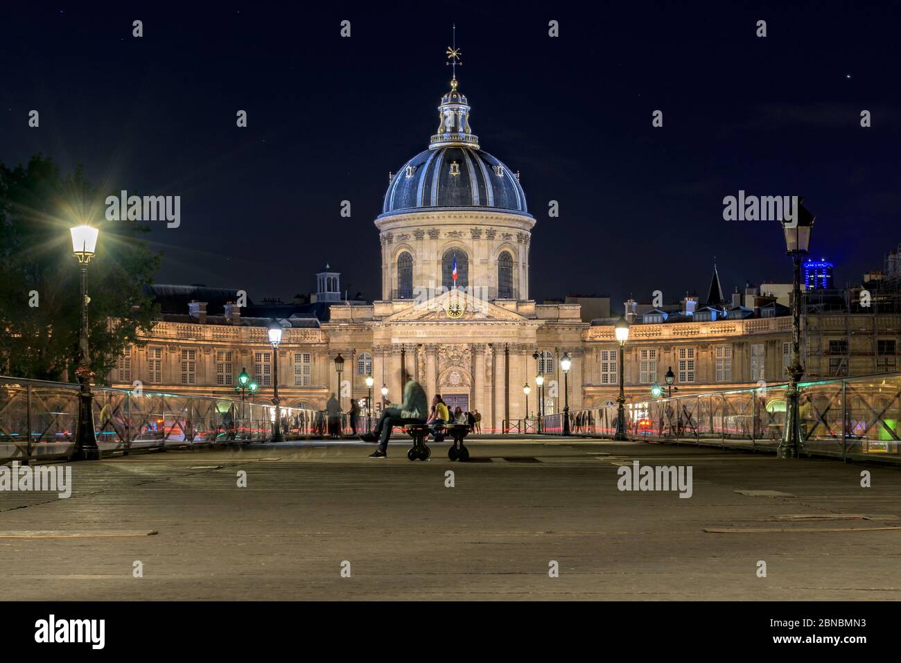 Paris, France. Night time long exposure of the Pont des Arts bridge and the illuminated Institut de France, grand cupola topped building baroque style. Stock Photo