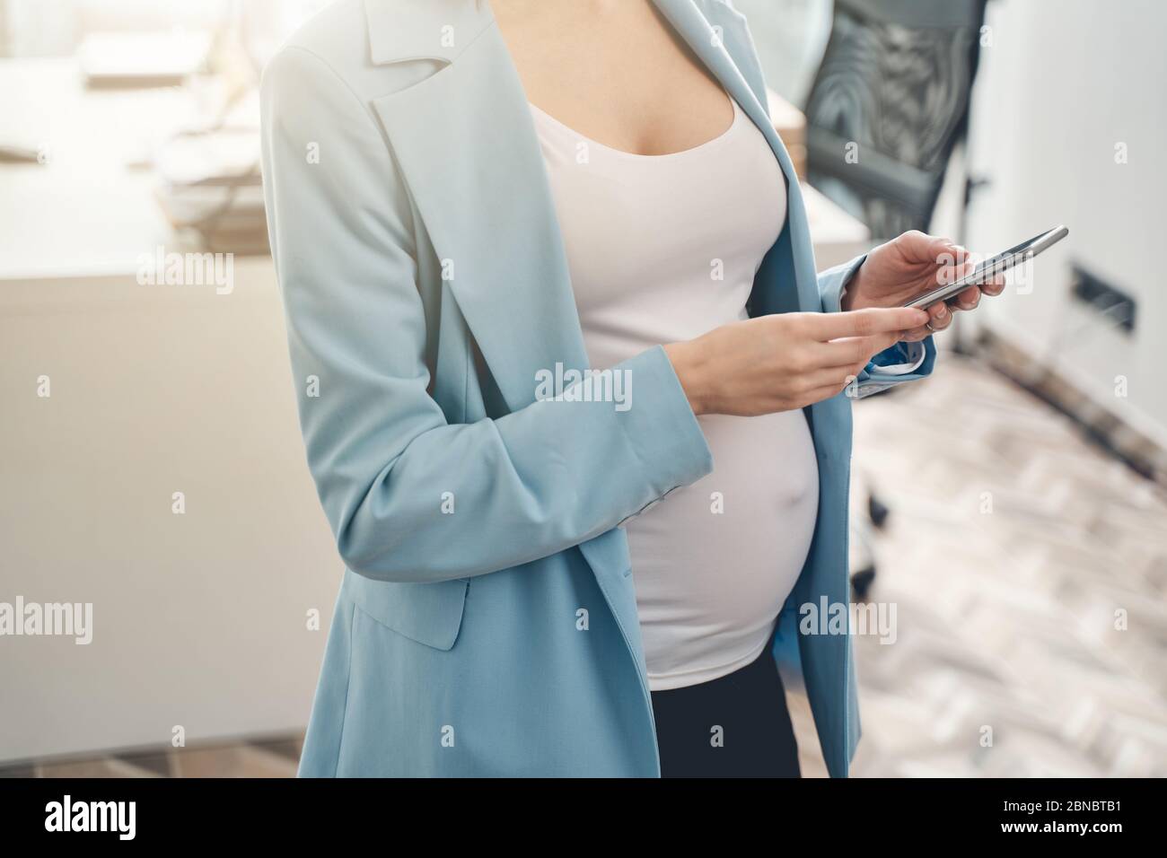 Young pregnant woman using cellphone at work Stock Photo