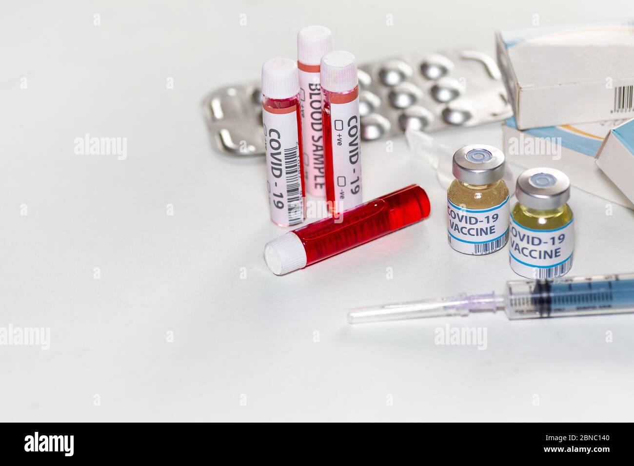 Vaccine bottles with injection syringe, blood sample vials and medical drugs at a healthcare center for detection and treatment of Coronavirus patient Stock Photo