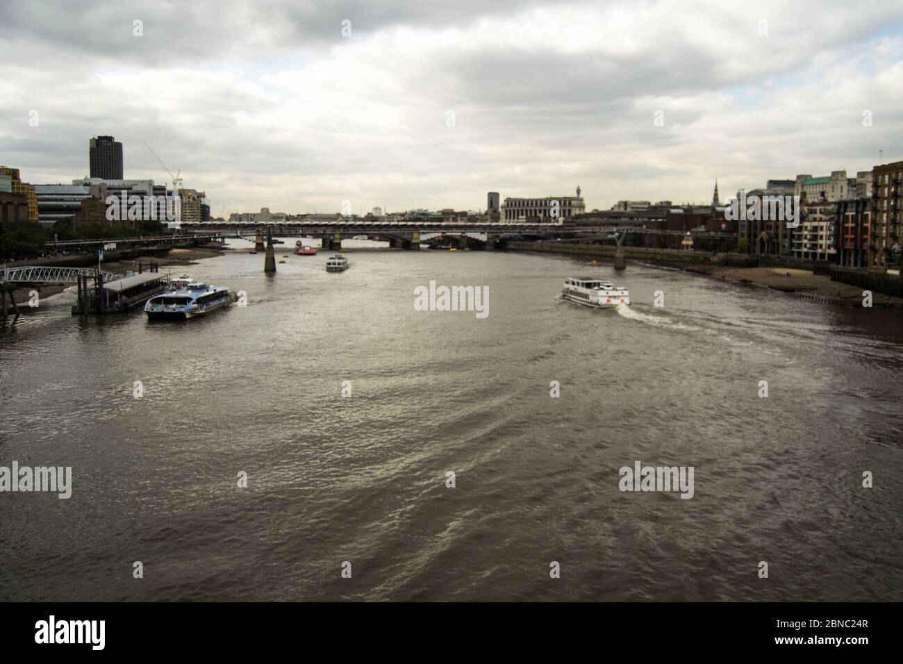 River with boats and a bridge over it with a cloudy sky Stock Photo