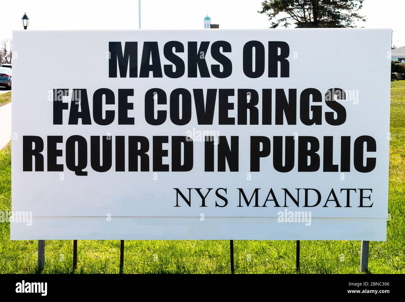 A sign on the side of the road reads Mask or Face Covering Required in Public as you enter a village in Long Island, New York. Stock Photo