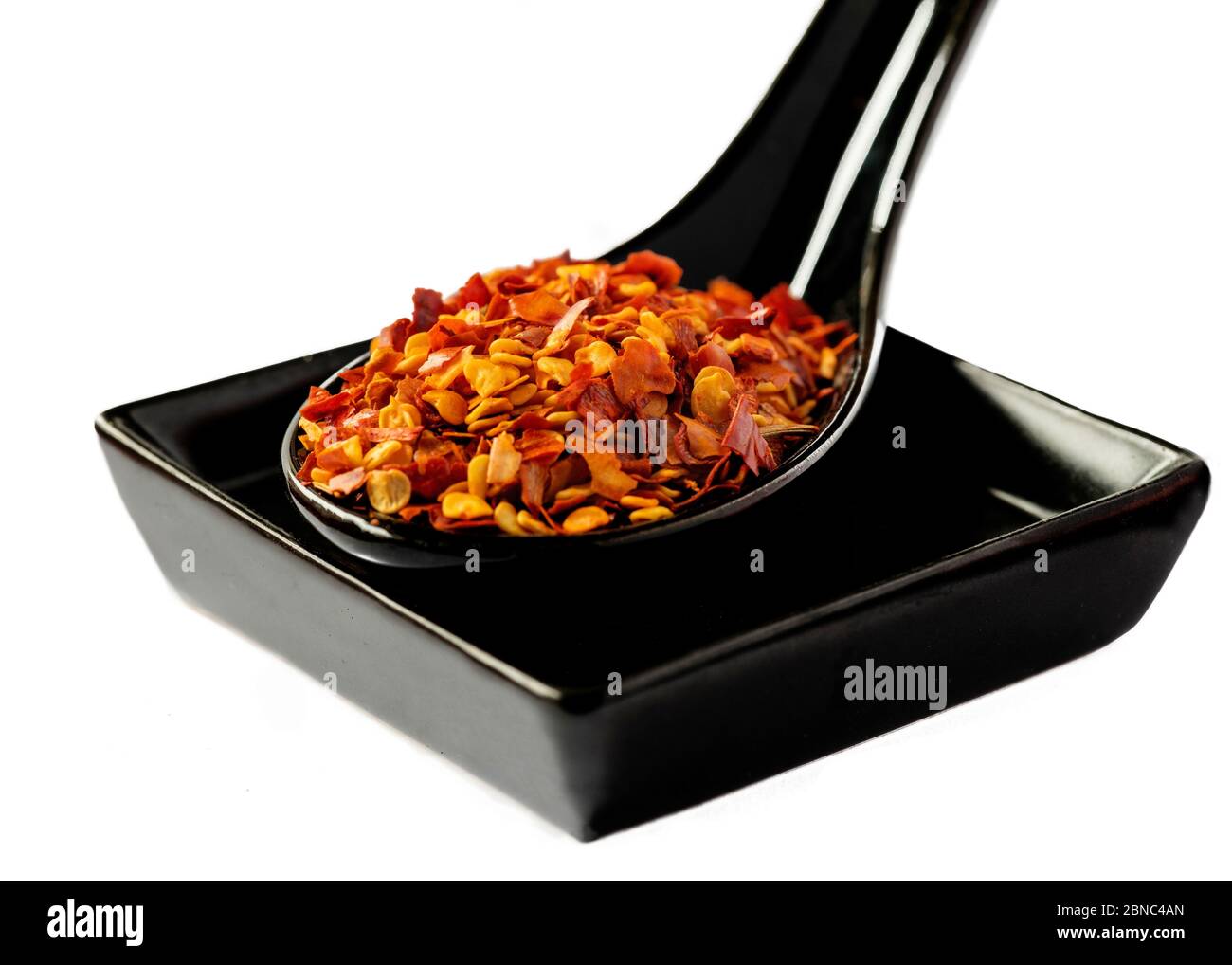 Ceramic spoon with dried red hot chili pepper and square plate isolated on white background Stock Photo