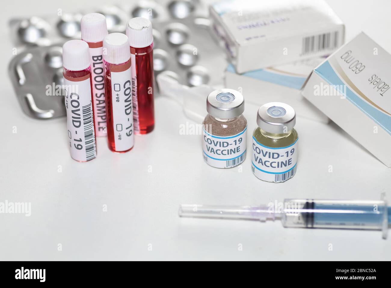 Vaccine bottles with injection syringe, blood sample vials and medical drugs at a healthcare center for detection and treatment of Coronavirus patient Stock Photo