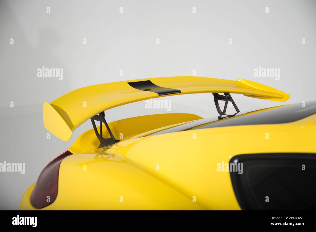 Closeup of a spoiler on a yellow modern sports car under the lights isolated on a grey background Stock Photo