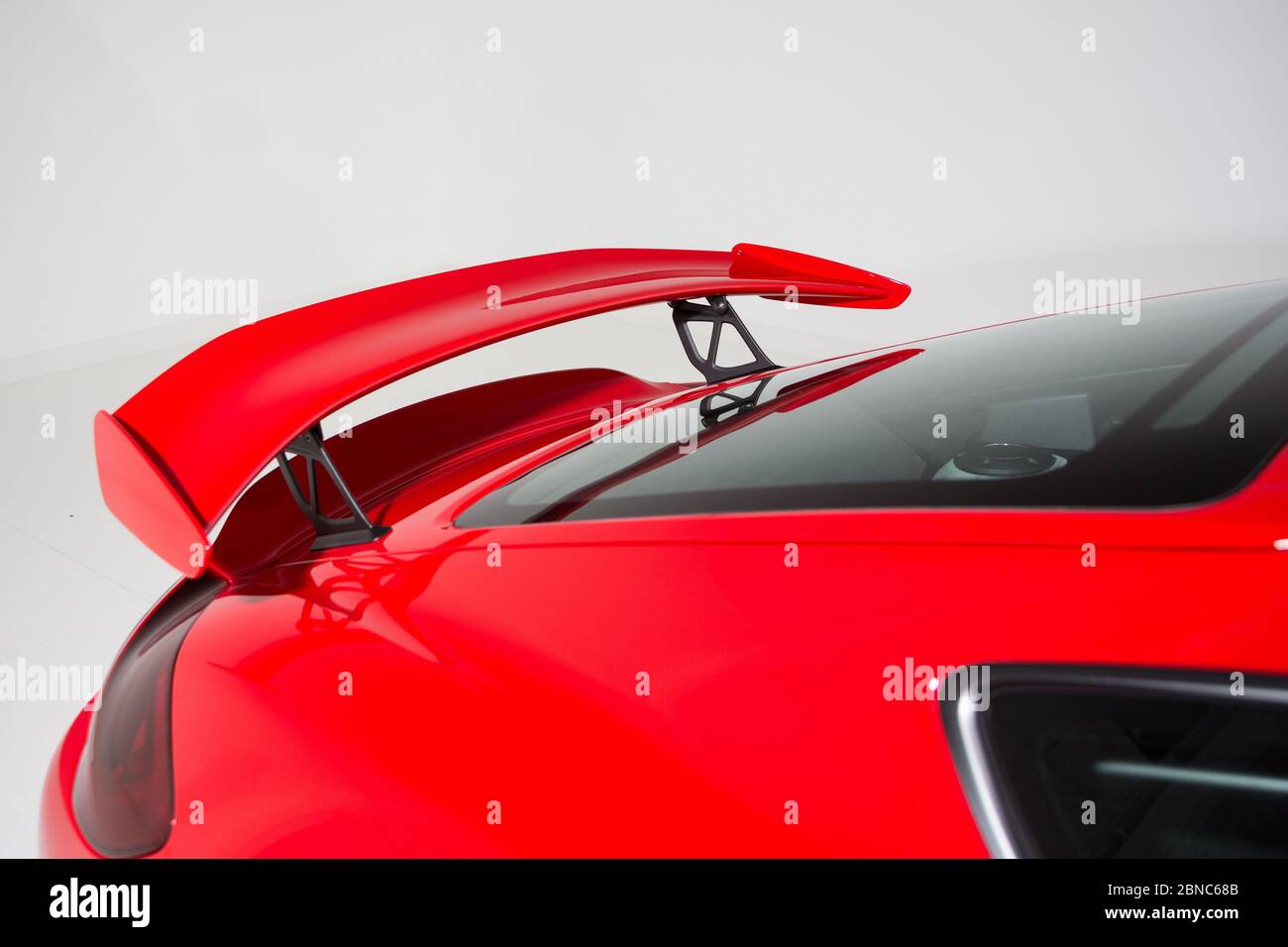 Closeup of a spoiler on a red modern car under the lights isolated on a grey background Stock Photo