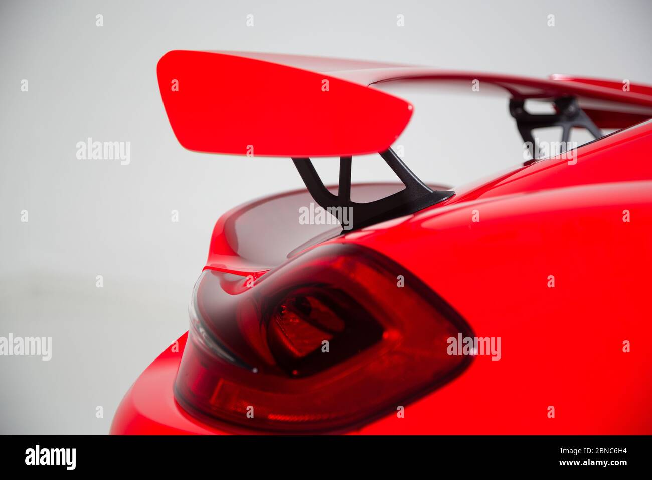 Closeup of a spoiler on a red modern sports car under the lights isolated on a grey background Stock Photo
